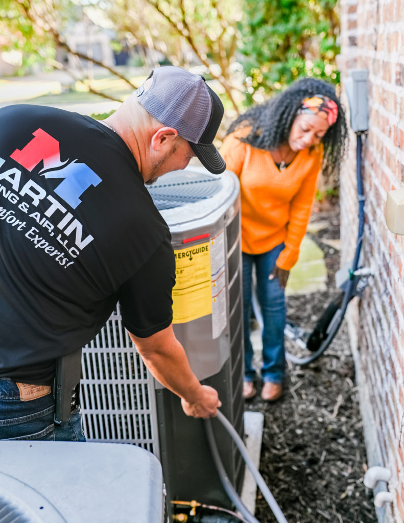 Martin Heating & Air technician showing an air conditioning unit connection to a customer